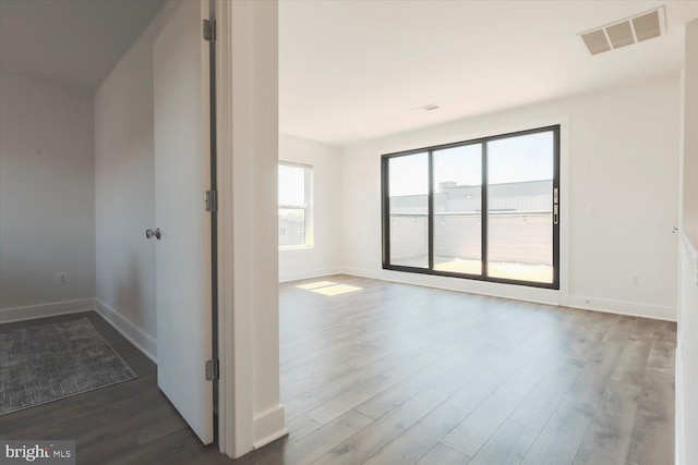empty room with visible vents, baseboards, and wood finished floors