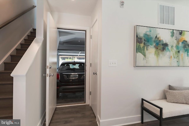 hallway with stairs, visible vents, baseboards, and wood finished floors