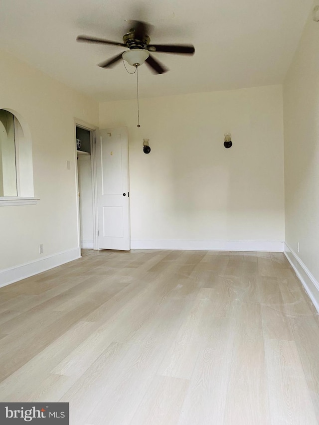 empty room with baseboards, ceiling fan, and light wood-type flooring