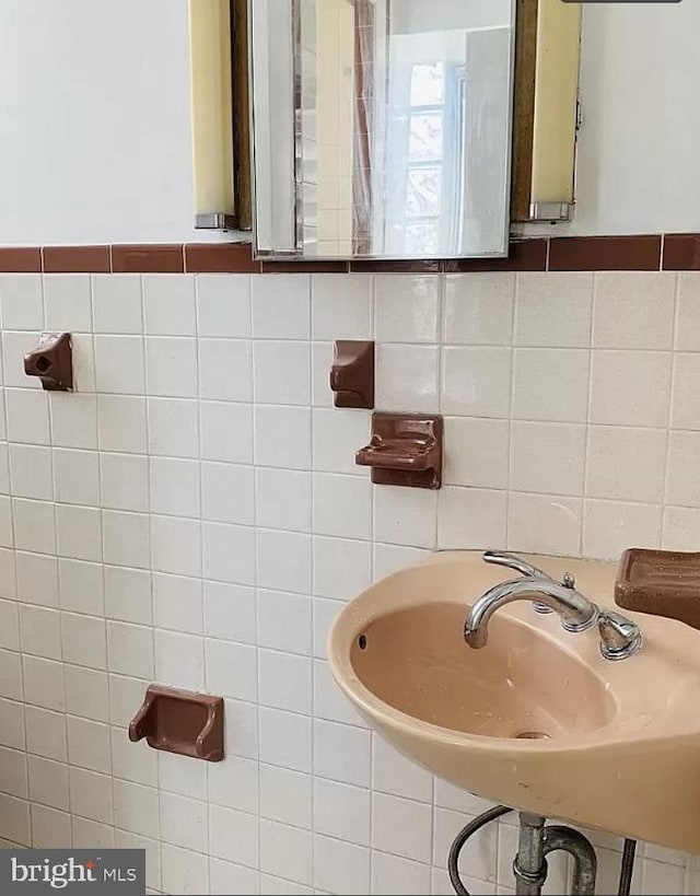 bathroom featuring a sink and tile walls