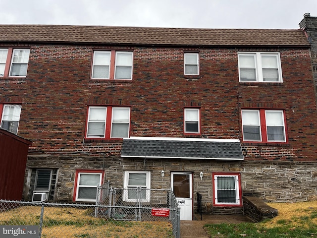 view of front of property featuring stone siding, fence, and brick siding