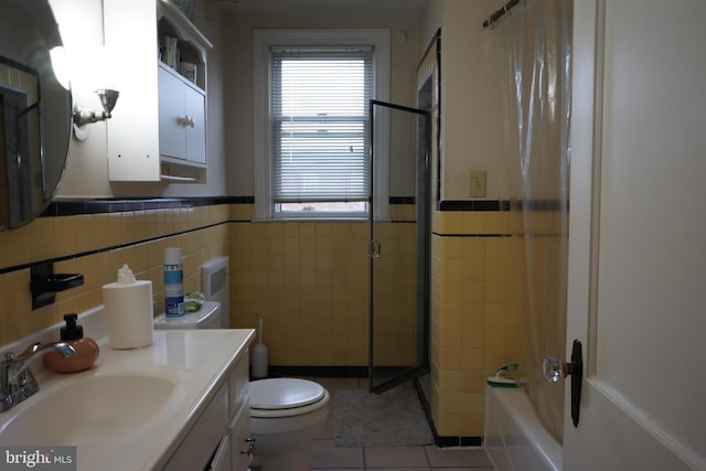 bathroom with tile walls, walk in shower, toilet, vanity, and tile patterned flooring