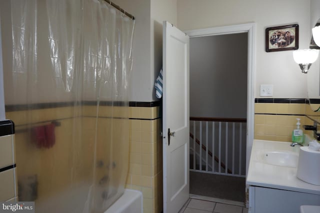 full bathroom with a wainscoted wall, tile patterned floors, vanity, shower / tub combo, and tile walls
