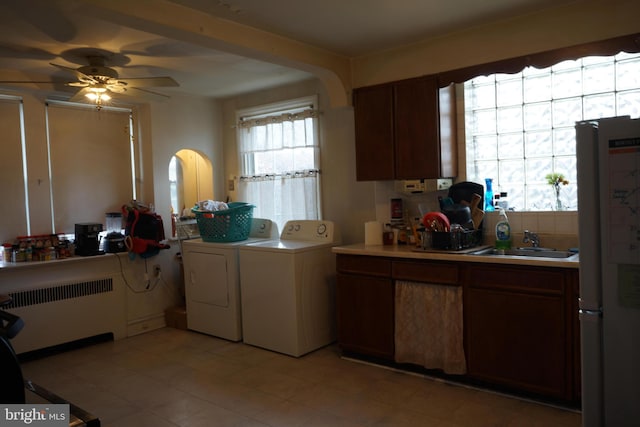 kitchen featuring light countertops, washer and clothes dryer, a sink, radiator heating unit, and freestanding refrigerator