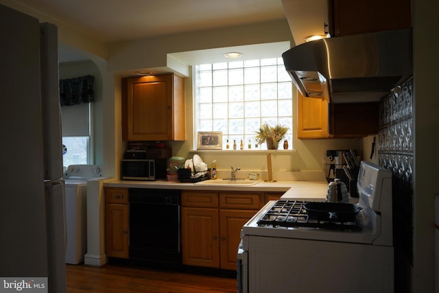 kitchen with light countertops, stainless steel microwave, under cabinet range hood, a sink, and gas range oven