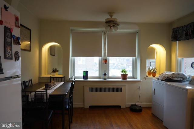 kitchen with radiator, washer and clothes dryer, ceiling fan, freestanding refrigerator, and wood finished floors