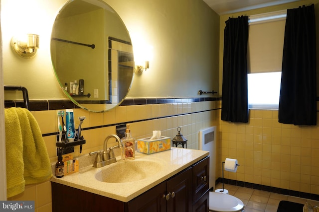 bathroom featuring toilet, vanity, wainscoting, tile patterned flooring, and tile walls