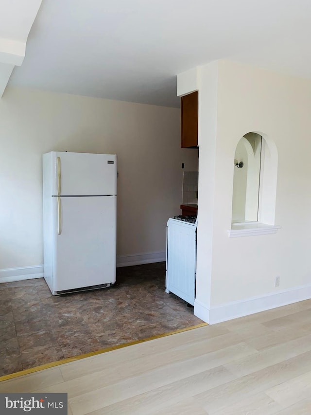 kitchen featuring wood finished floors, baseboards, and white appliances