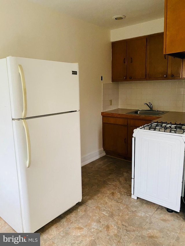 kitchen with tile counters, gas stove, a sink, backsplash, and freestanding refrigerator