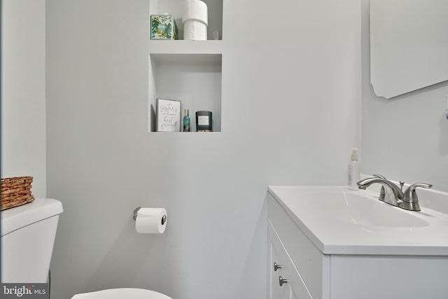 half bath featuring vanity and toilet