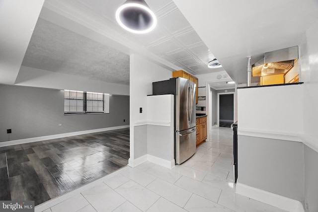 kitchen featuring brown cabinets, marble finish floor, freestanding refrigerator, baseboards, and open floor plan