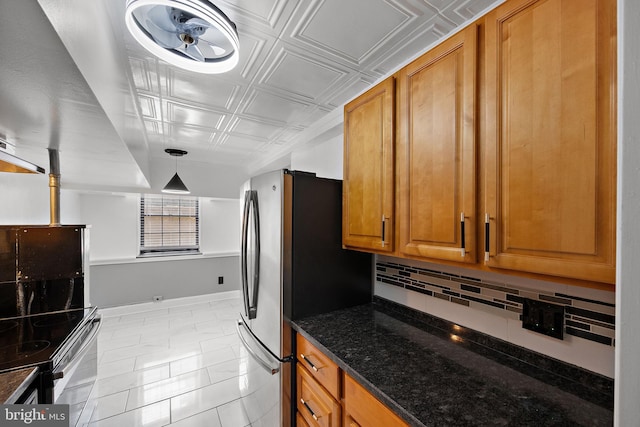 kitchen featuring brown cabinets, an ornate ceiling, dark stone countertops, baseboards, and decorative backsplash