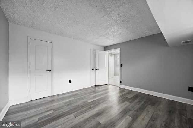 spare room featuring baseboards, a textured ceiling, visible vents, and wood finished floors
