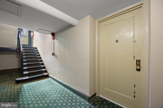 stairway featuring baseboards and carpet flooring