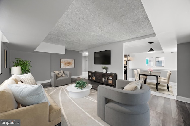 living room with baseboards, a textured ceiling, and wood finished floors