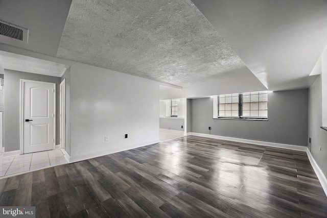 interior space with a textured ceiling, baseboards, visible vents, and wood finished floors