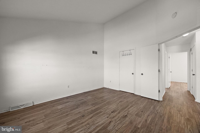 unfurnished bedroom with a closet, baseboards, dark wood-style floors, and visible vents