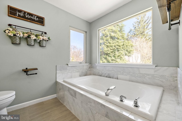 full bathroom with toilet, baseboards, and a bath