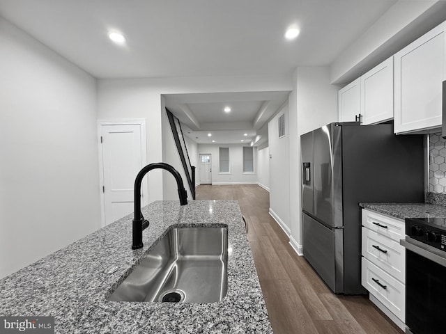 kitchen with a sink, white cabinetry, stove, dark wood-type flooring, and stone counters