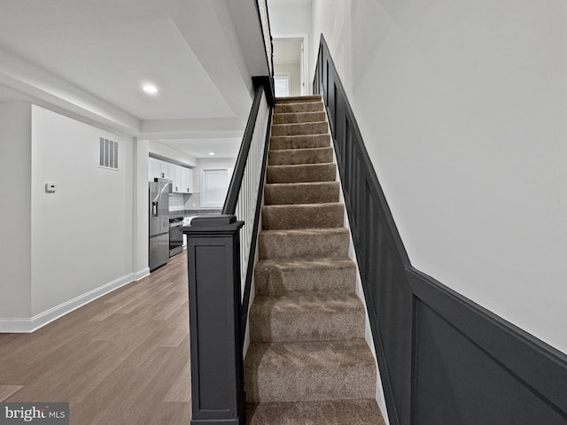stairs featuring recessed lighting, visible vents, baseboards, and wood finished floors