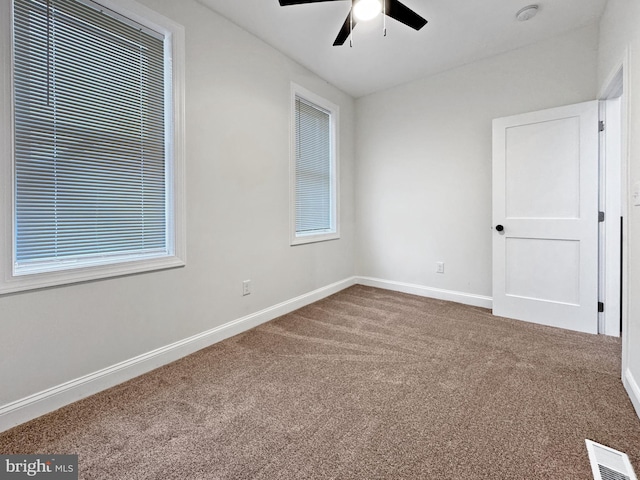 carpeted empty room featuring baseboards, a ceiling fan, and visible vents