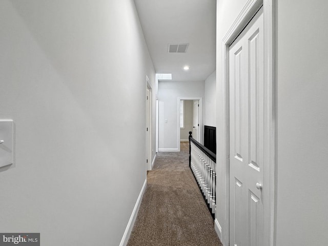hall featuring carpet flooring, visible vents, and baseboards