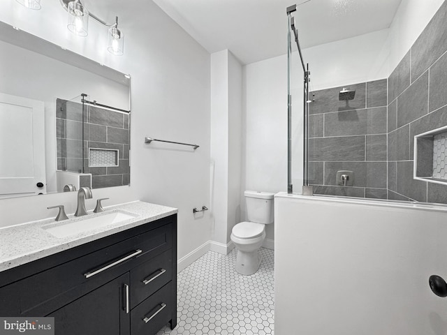 bathroom with baseboards, toilet, a walk in shower, vanity, and tile patterned flooring