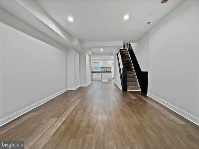 unfurnished living room with recessed lighting, baseboards, dark wood finished floors, and stairway