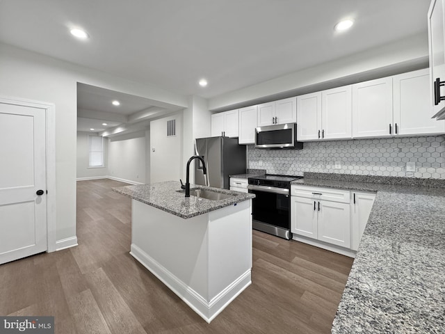 kitchen with dark wood-style floors, white cabinets, visible vents, stainless steel appliances, and a sink