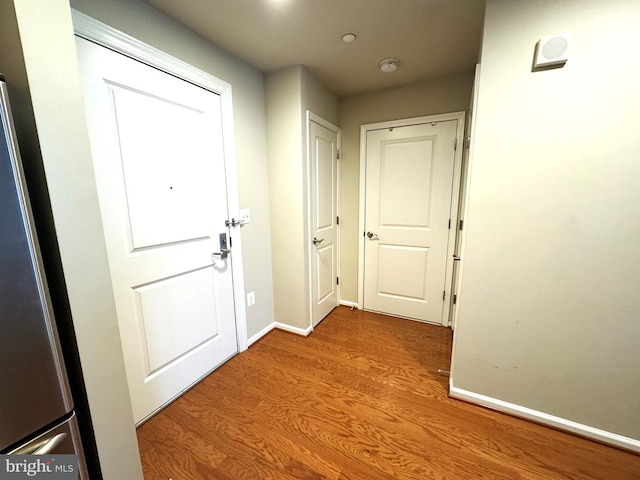 corridor with baseboards and wood finished floors