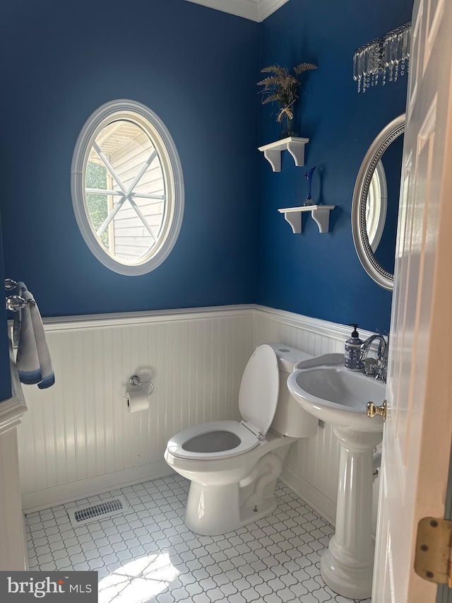 bathroom featuring toilet, tile patterned floors, visible vents, and a wainscoted wall