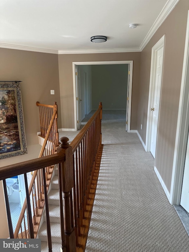corridor featuring carpet floors, baseboards, an upstairs landing, and ornamental molding