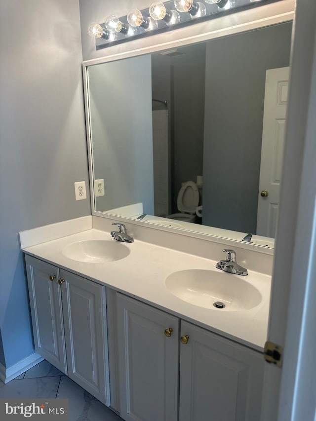 full bathroom featuring double vanity, a sink, marble finish floor, and baseboards