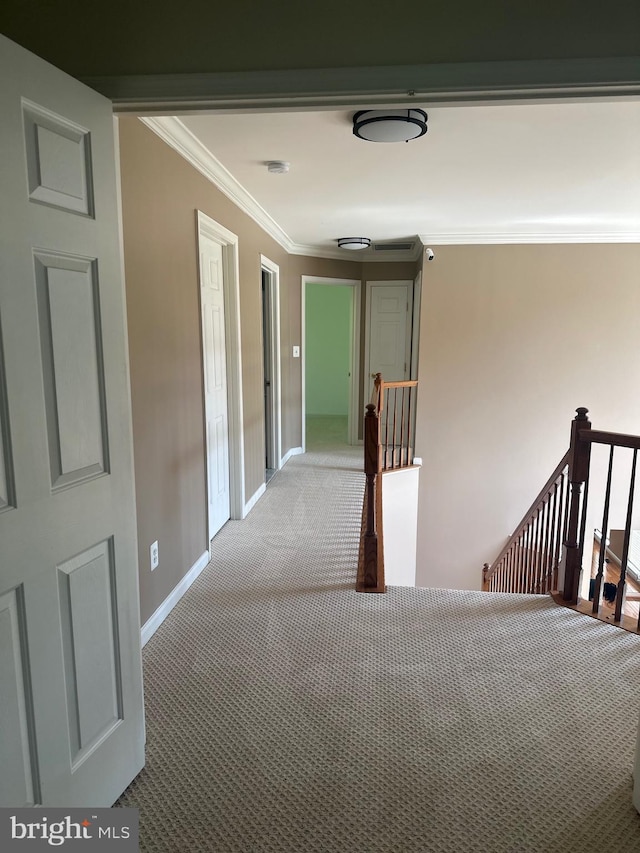 hall featuring crown molding, carpet floors, baseboards, and an upstairs landing