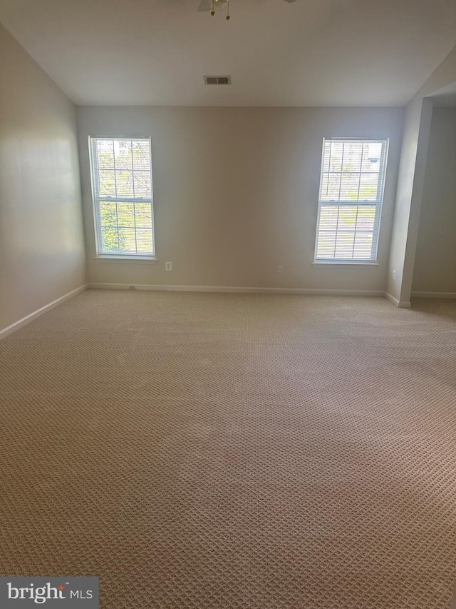 unfurnished room with baseboards, visible vents, and light carpet