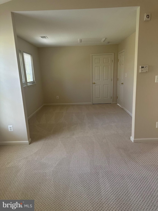 empty room with baseboards, visible vents, and light carpet