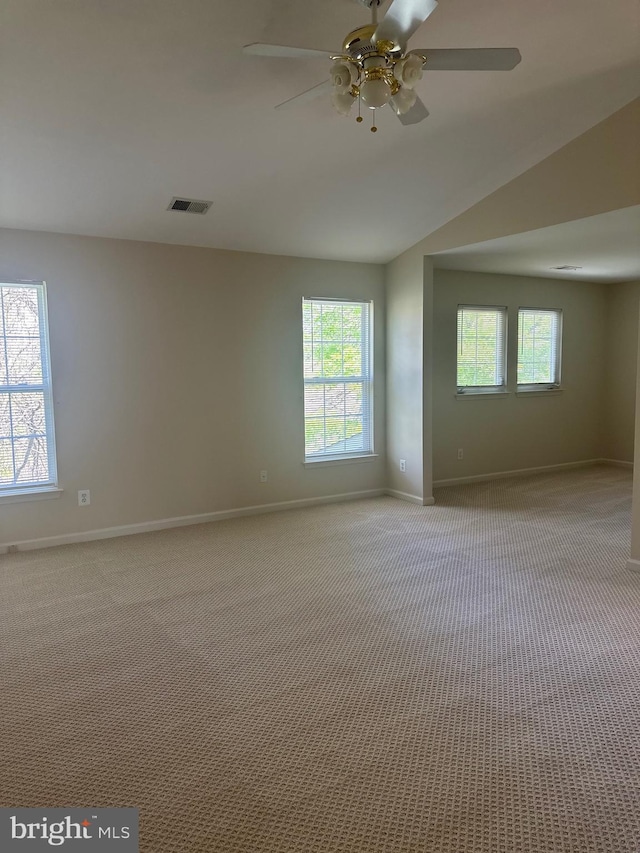 carpeted empty room featuring a healthy amount of sunlight, baseboards, and visible vents