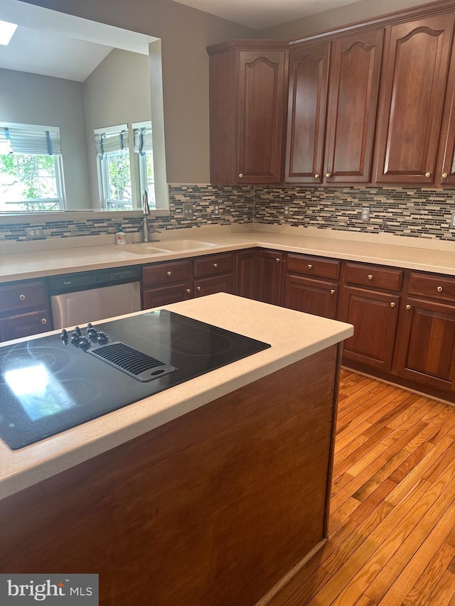 kitchen with light countertops, black electric cooktop, backsplash, and dishwasher