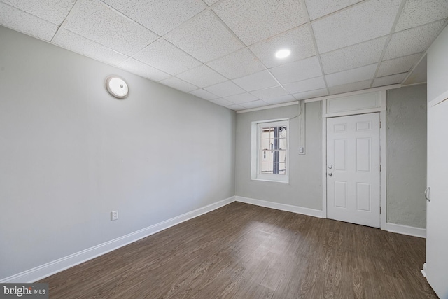 interior space featuring a paneled ceiling, wood finished floors, and baseboards