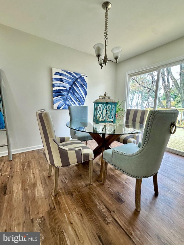 dining space featuring baseboards, wood finished floors, and a chandelier