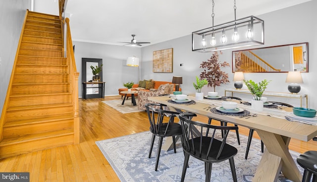 dining area featuring light wood-style flooring, stairway, and a ceiling fan