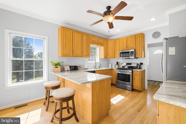 kitchen featuring visible vents, ornamental molding, appliances with stainless steel finishes, a peninsula, and backsplash