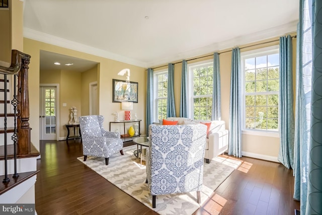 sitting room featuring baseboards, dark wood-style flooring, ornamental molding, and stairway