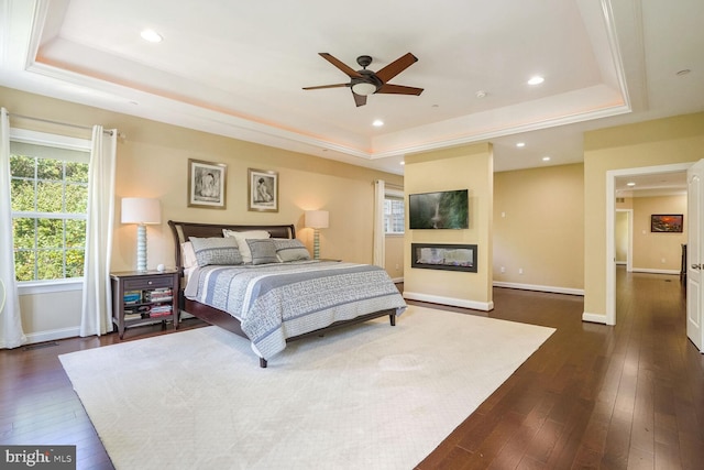 bedroom featuring baseboards, dark wood finished floors, and a raised ceiling