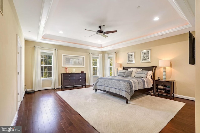 bedroom featuring baseboards, dark wood-style floors, a tray ceiling, and multiple windows