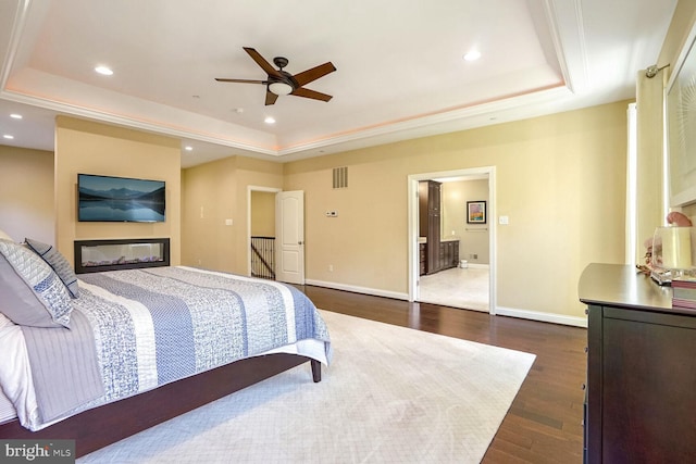 bedroom featuring baseboards, dark wood-style floors, visible vents, and a raised ceiling