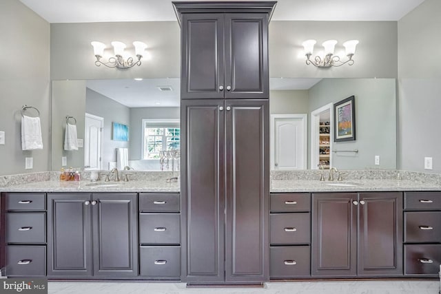full bath featuring visible vents, a sink, and two vanities