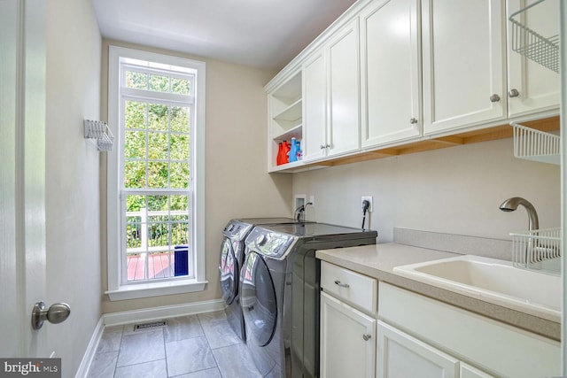 clothes washing area with baseboards, a sink, visible vents, cabinet space, and washing machine and dryer