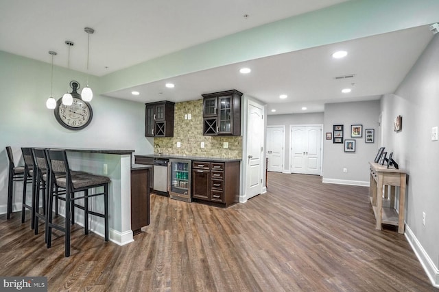 kitchen with wine cooler, a breakfast bar area, tasteful backsplash, glass insert cabinets, and dark wood-type flooring