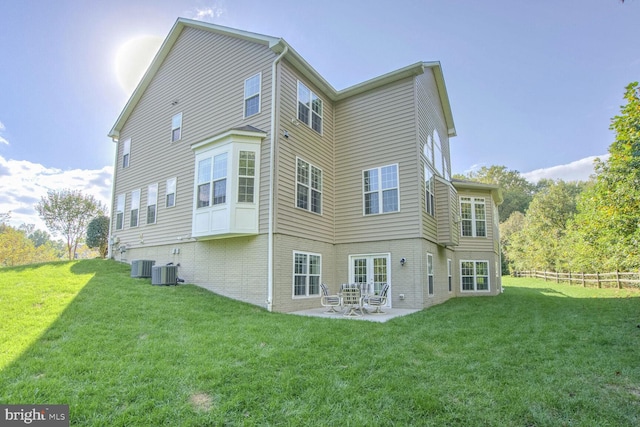 back of house with central air condition unit, a lawn, a patio area, and brick siding